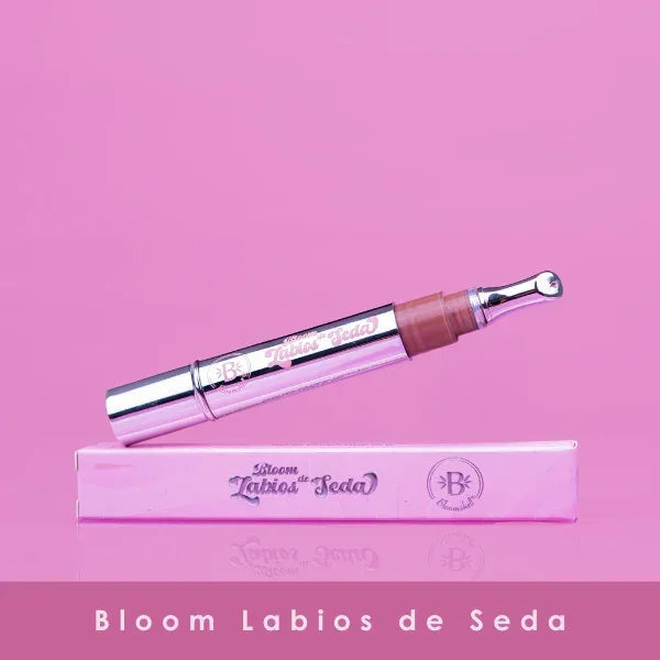 Bloom Labios de Seda: Brillo Labial Hidratante con aplicador metálico sobre caja rosa. Ideal para hidratación y suavidad de labios.
